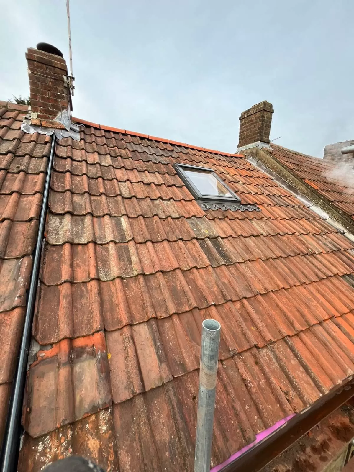 A roof with orange corrugated tiling and a new skylight in the centre